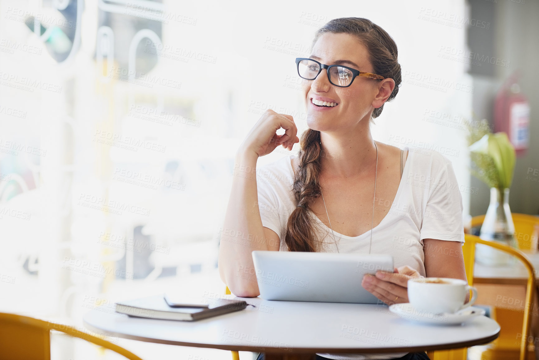 Buy stock photo Shot of a relaxed young woman using her tablet while drinking coffee at her favorite cafe