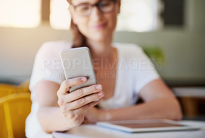Buy stock photo Shot of a relaxed young woman using her smartphone while chilling in her favorite cafe