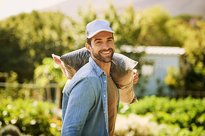 Buy stock photo Portrait of a happy young farmer carrying a bag of compost over his shoulder on the farm