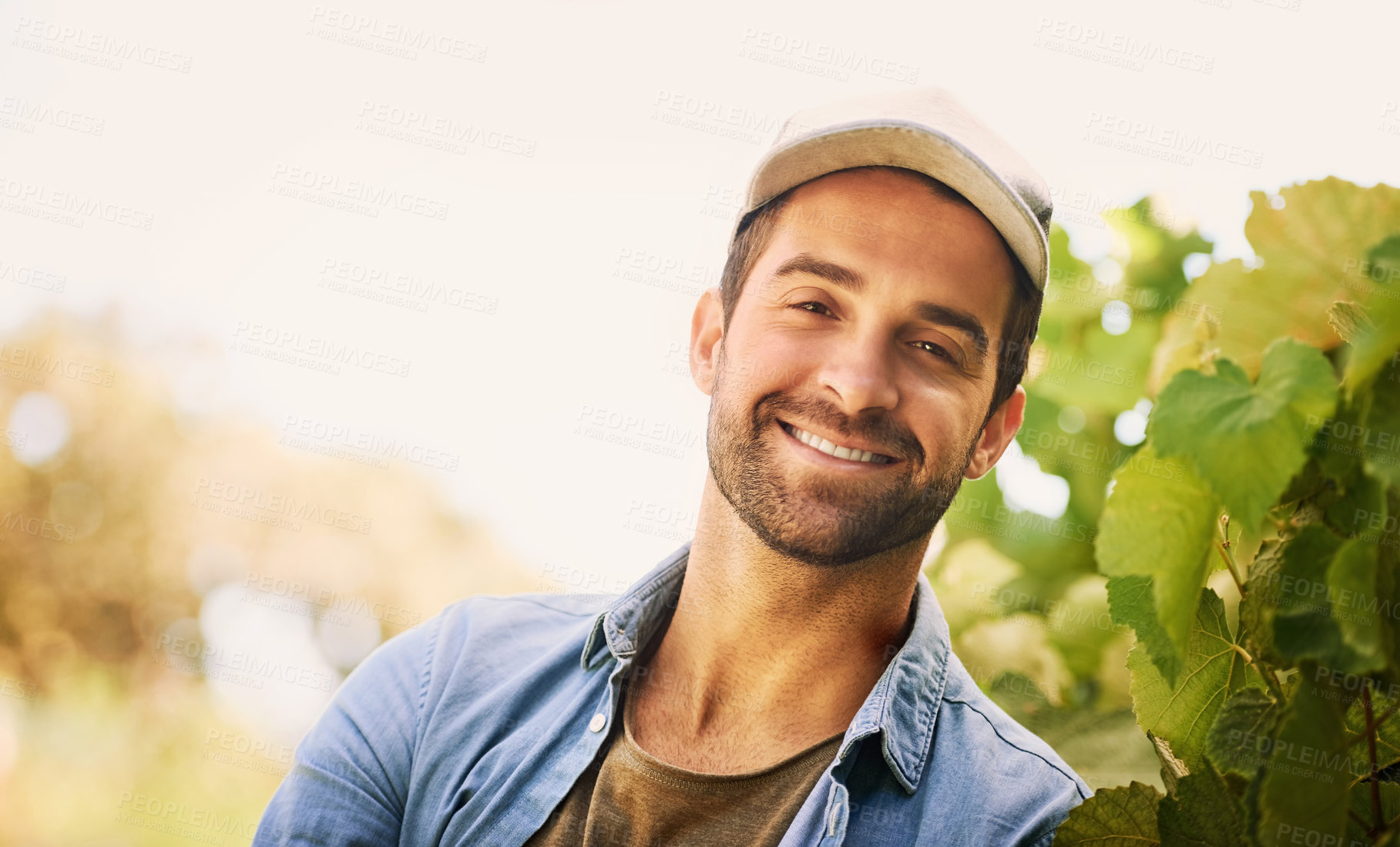 Buy stock photo Portrait of a cheerful young farmer posing in the fields on his farm