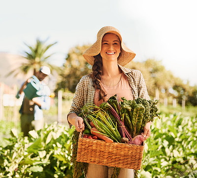 Buy stock photo Portrait of a happy young farmer harvesting herbs and vegetables in a basket on her farm