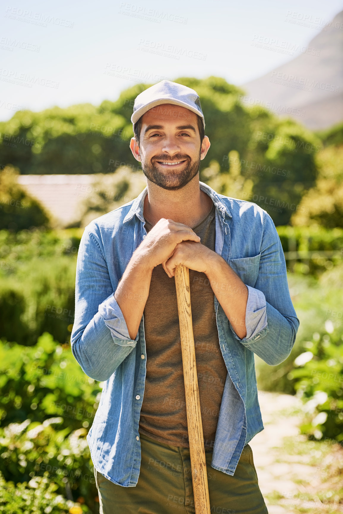 Buy stock photo Portrait of a happy young farmer holding a spade while posing in the fields on his farm
