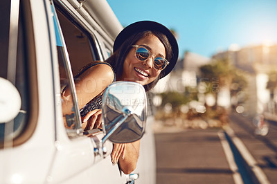 Buy stock photo Shot of a happy young woman leaning out of the window during a road trip