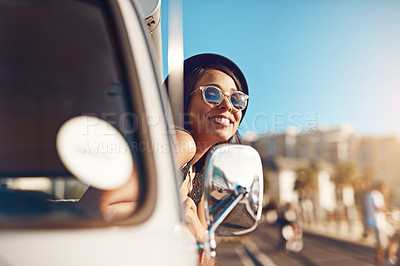 Buy stock photo Shot of a happy young woman leaning out of the window during a road trip