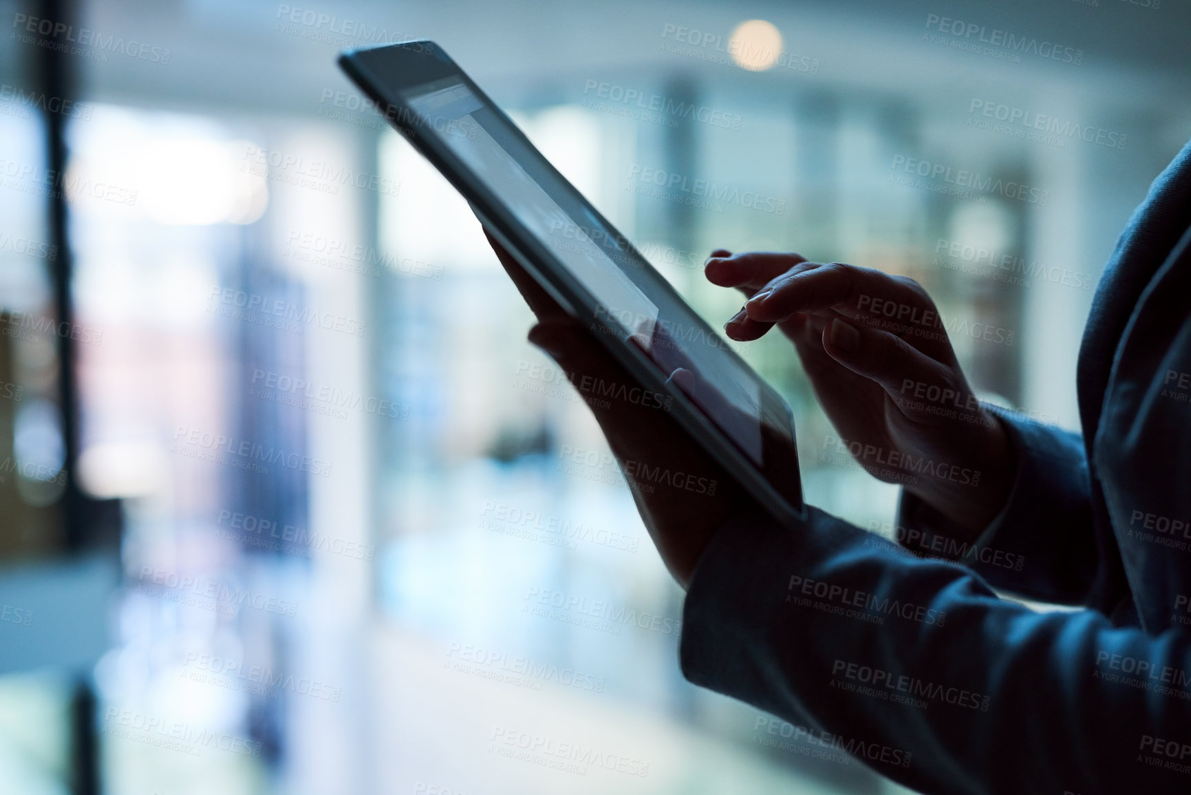 Buy stock photo Cropped shot of an unrecognizable businesswoman working on a digital tablet in her office late into the night