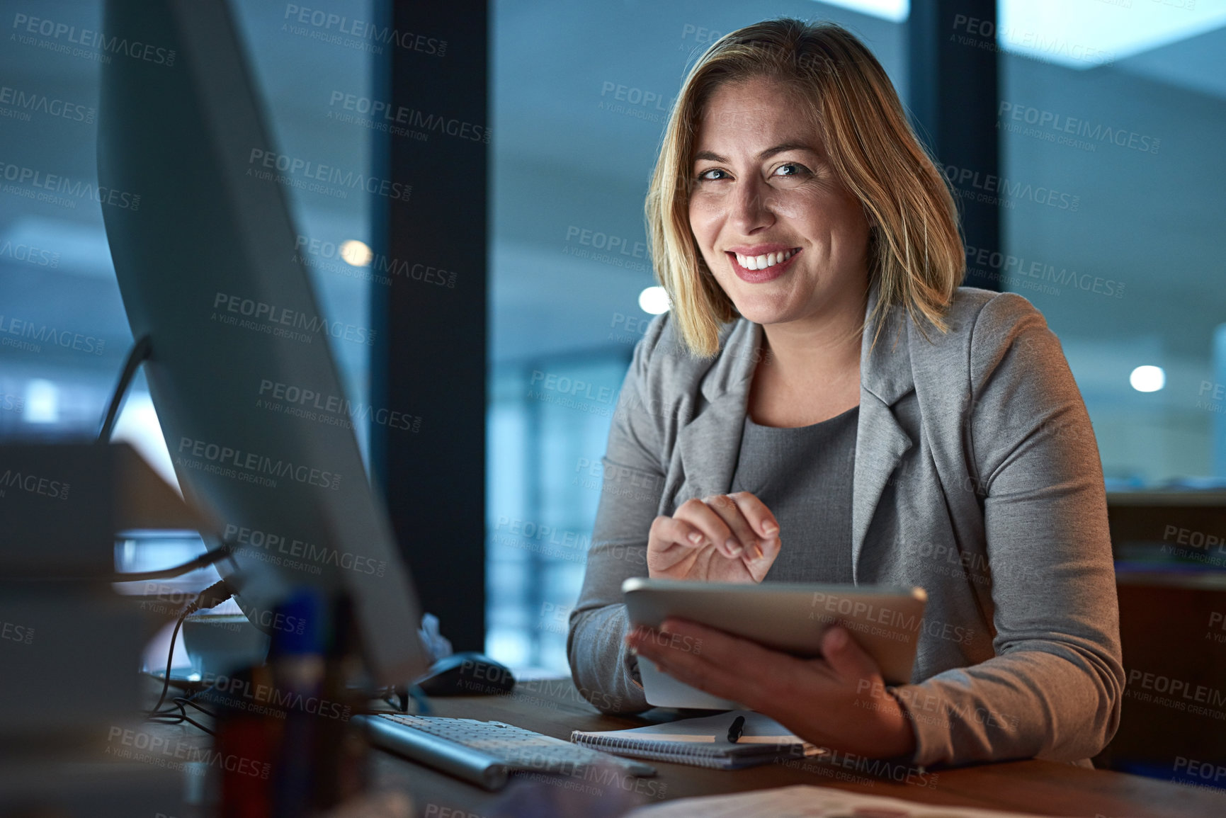 Buy stock photo Cropped portrait of a businesswoman working on a digital tablet in her office late into the night