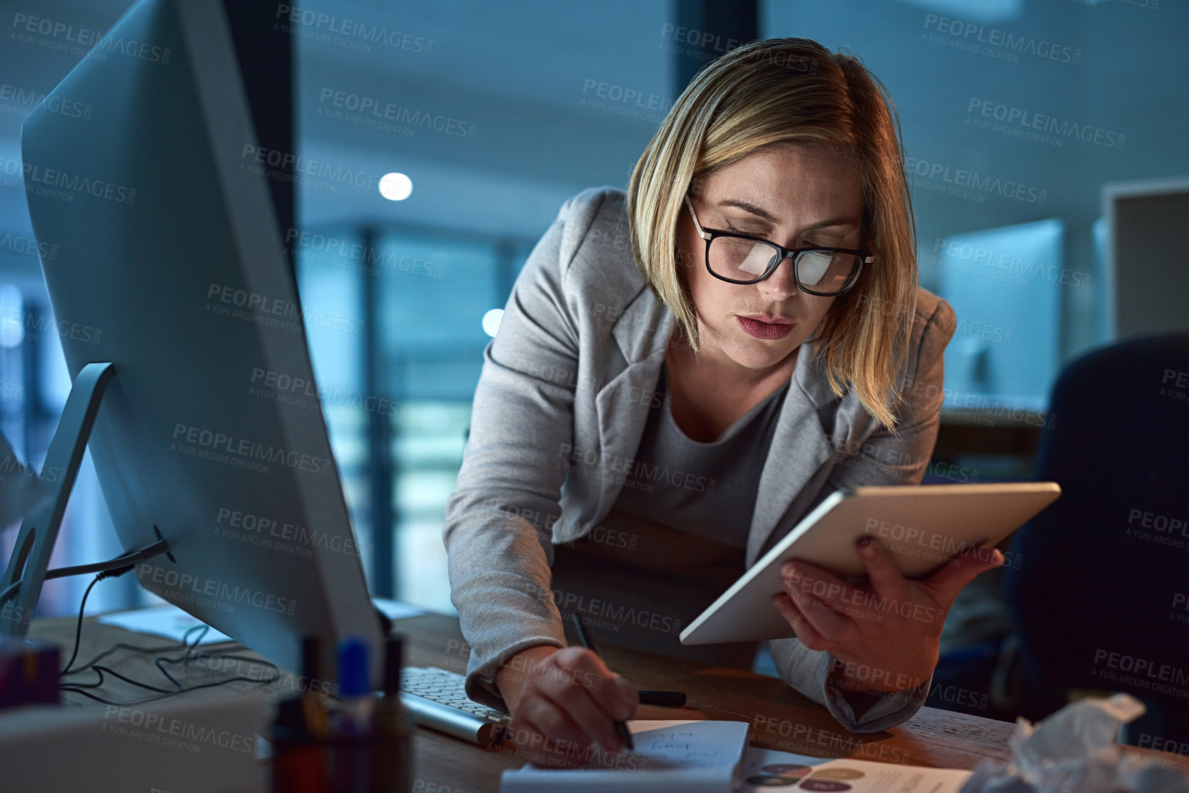 Buy stock photo Cropped shot of a businesswoman working on a digital tablet in her office late into the night