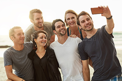 Buy stock photo Shot of a group of happy young friends posing for a selfie together on the beach