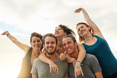 Buy stock photo Portrait of a group of happy young friends posing with their arms around each other on the beach