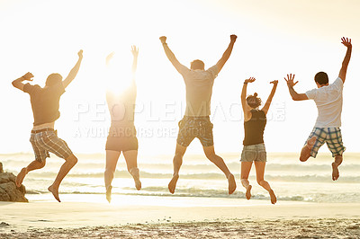 Buy stock photo Rearview shot of a group of unidentifiable friends jumping together on the beach at sunset