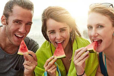 Buy stock photo Portrait of a group of happy young friends eating watermelon together on the beach