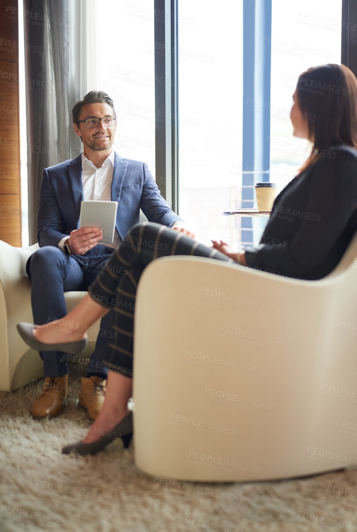 Buy stock photo Shot of two business people having a discussion in a modern office