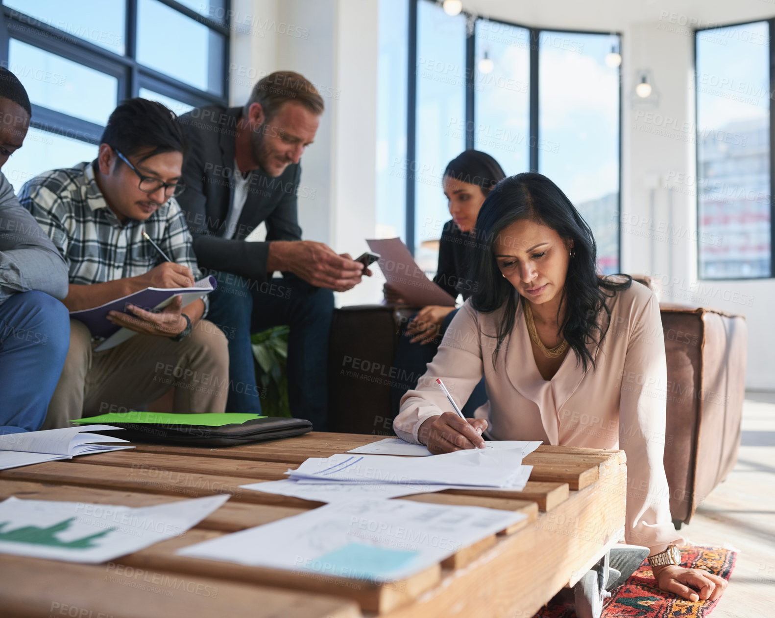 Buy stock photo Shot of a team of creative colleagues making notes during a meeting in their office