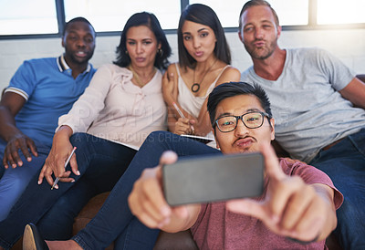 Buy stock photo Shot of a happy group of creative colleagues posing for a selfie together in the office