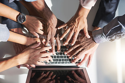 Buy stock photo High angle shot of a group of colleagues posing with their hands over a laptop in the office