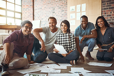 Buy stock photo Shot of a team of entrepreneurs collaborating and sitting on the floor in a modern office