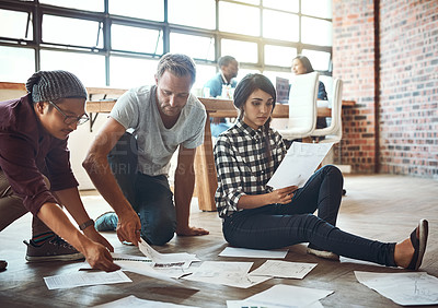Buy stock photo Shot of a team of entrepreneurs collaborating and sitting on the floor in a modern office