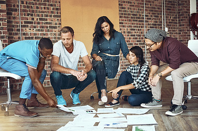 Buy stock photo Shot of a team of entrepreneurs collaborating sitting on the floor in a modern office