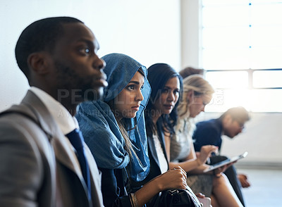 Buy stock photo Shot of a group of well-dressed businesspeople seated in line while waiting to be interviewed