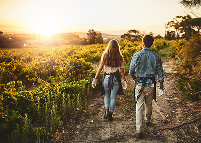 Buy stock photo Rearview shot of a young man and woman walking though a farm