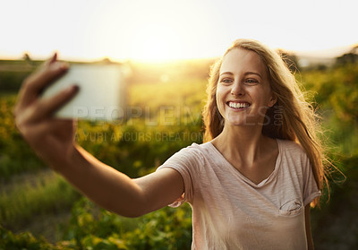Buy stock photo Shot of a happy young woman taking a photo of herself and her farm in the background