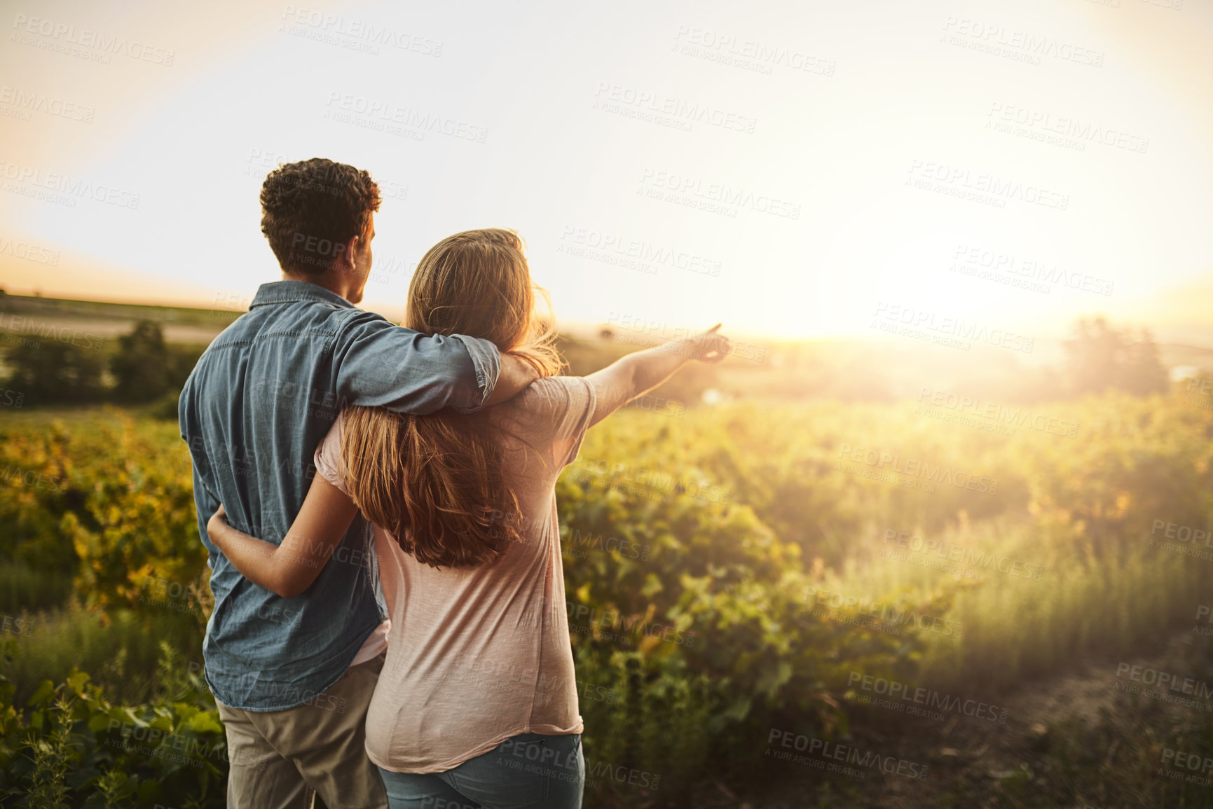 Buy stock photo Back, hug and couple in sunrise, pointing and together with care, love and date for anniversary in outdoor. Morning, partner and person with embrace, nature and peace in field and relax in Texas