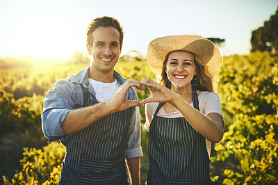 Buy stock photo Shot of a young couple holding up their hands together making a heart shape with their crops in the background