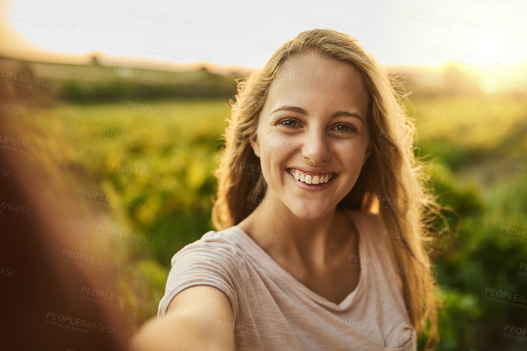Buy stock photo Shot of a happy young woman taking a photo of herself and her farm in the background
