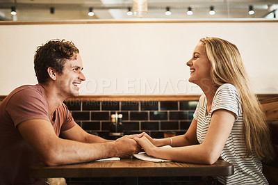 Buy stock photo Shot of a happy young student couple holding hands while studying together at a cafe
