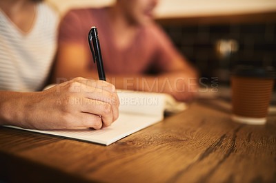 Buy stock photo Cropped shot of two unidentifiable students having a study session at a cafe table