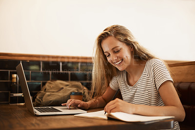 Buy stock photo Shot of a happy young student using her laptop to study at a cafe table