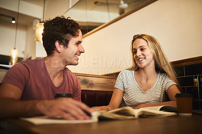 Buy stock photo Shot of two happy young students having a study session at their favorite cafe