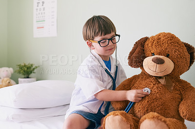 Buy stock photo Shot of a little boy pretending to be a doctor while examining his teddybear