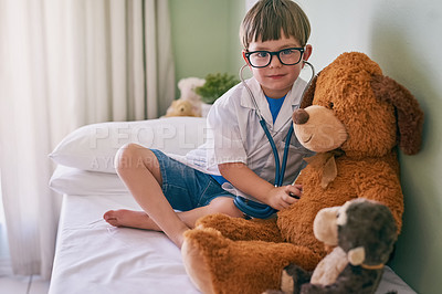 Buy stock photo Shot of a little boy pretending to be a doctor while examining his teddybear