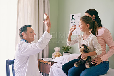 Buy stock photo Shot of a doctor giving his young patient a high five after her checkup