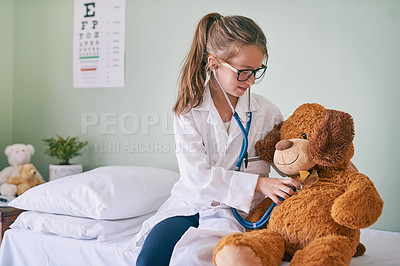 Buy stock photo Shot of a little girl pretending to be a doctor while examining her teddybear