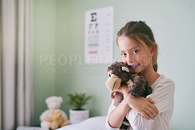 Buy stock photo Shot of a little girl holding her stuffed monkey while visiting the doctor