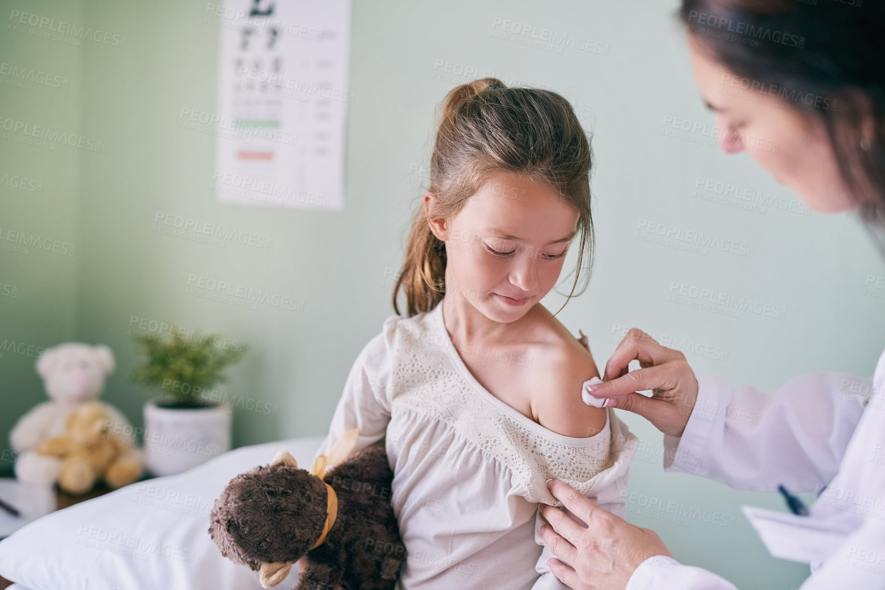 Buy stock photo Shot of a pediatrician cleaning her young patients arm with a cotton ball