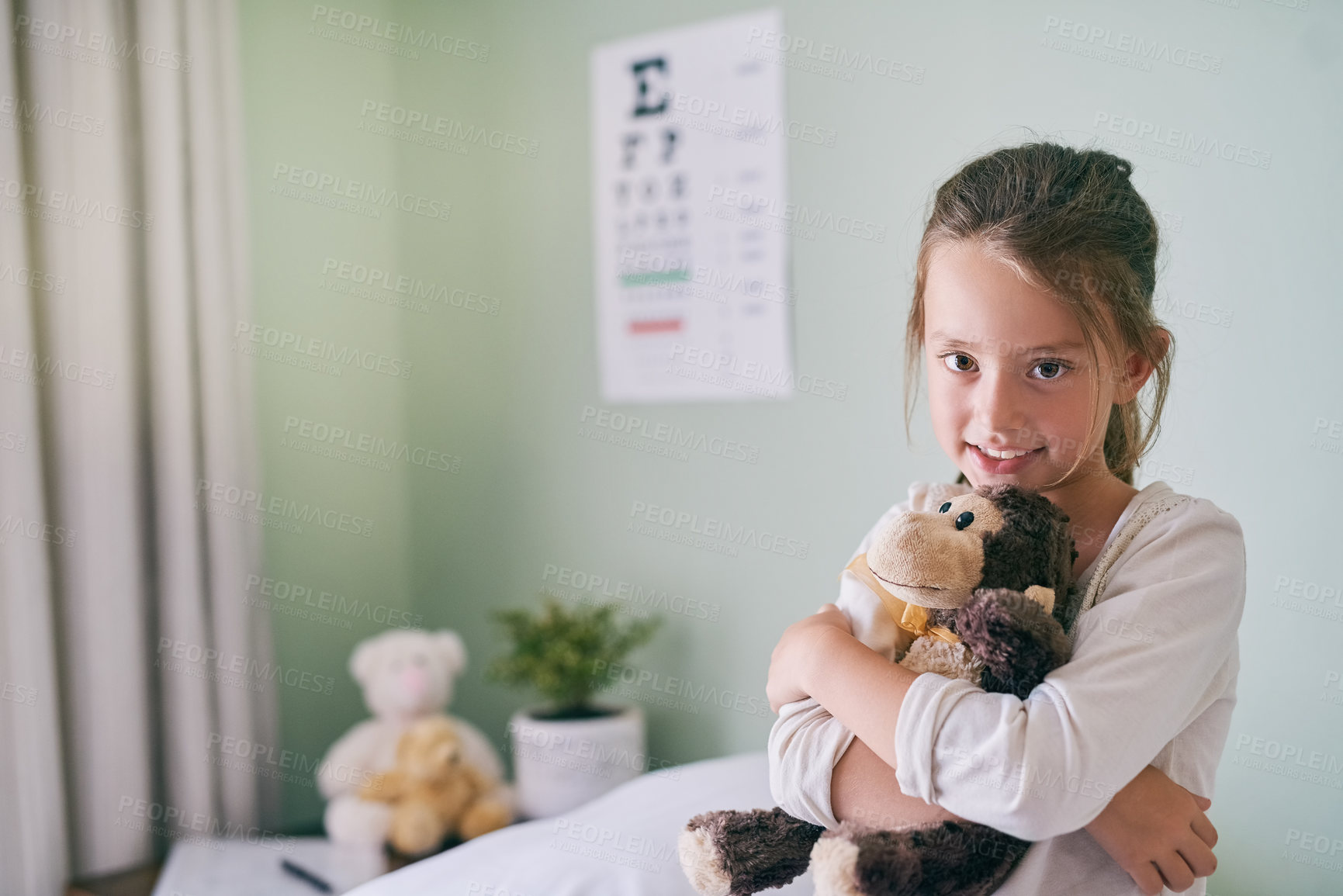 Buy stock photo Shot of a little girl holding her stuffed monkey while visiting the doctor