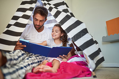 Buy stock photo Cropped shot of a father reading a book with his little daughter in a tent at home