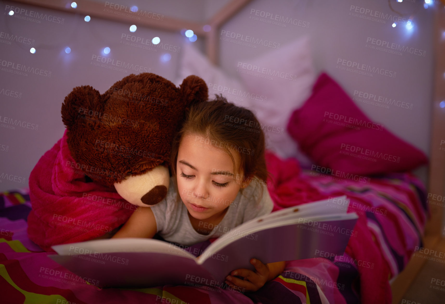 Buy stock photo Cropped shot of a little girl reading a book in bed with her teddybear