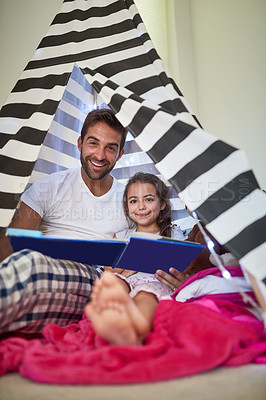 Buy stock photo Portrait of a father reading a book with his little daughter in a tent at home