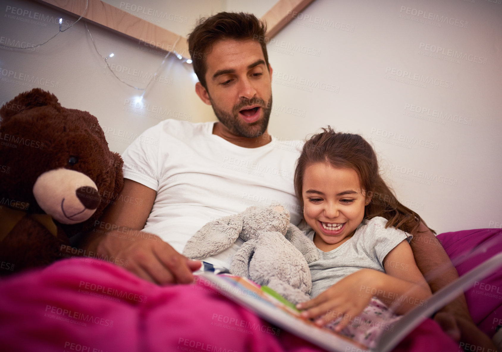 Buy stock photo Cropped shot of a father reading a book with his little daughter in bed at home