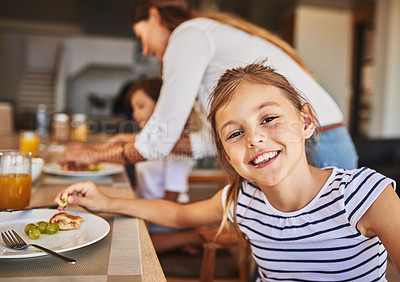 Buy stock photo Portrait of a little girl having breakfast with her family in the background