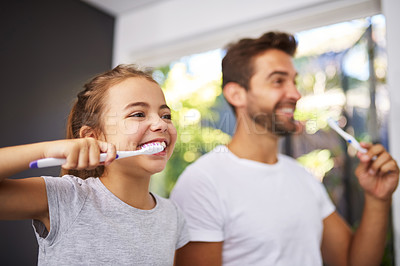 Buy stock photo Cropped shot of a handsome Dad and his daughter brushing their teeth in the bathroom