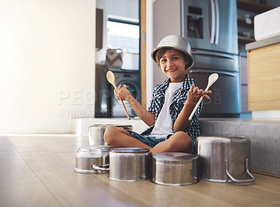 Buy stock photo Portrait of a happy little boy playing drums with pots on the kitchen floor while wearing a bowl on his head