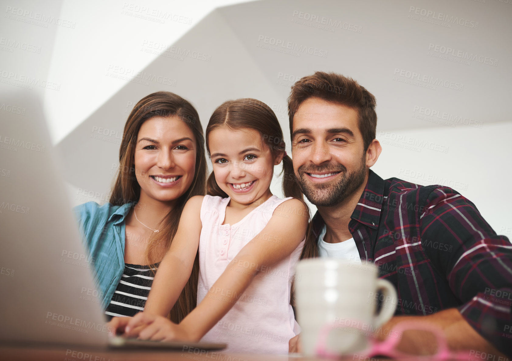 Buy stock photo Portrait of a happy married couple and their young daughter using a laptop together at home
