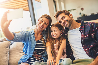 Buy stock photo Shot of a mother and father taking a selfie with their daughter on the sofa at home