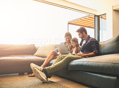 Buy stock photo Shot of a mother and father using a laptop with their daughter on the sofa at home