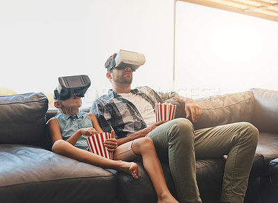 Buy stock photo Shot of a father and daughter eating popcorn and watching movies with virtual reality headsets at home